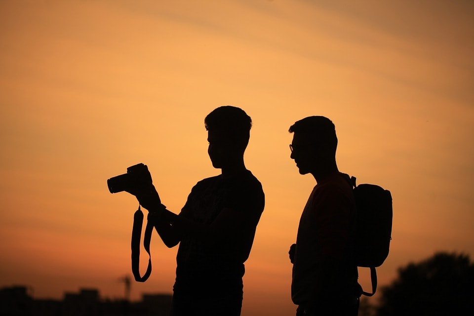 two men looking at a camera at sunset