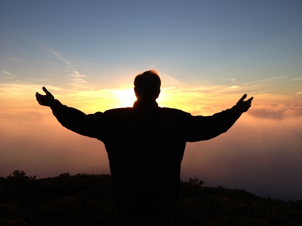 person with arms in sky at sunrise